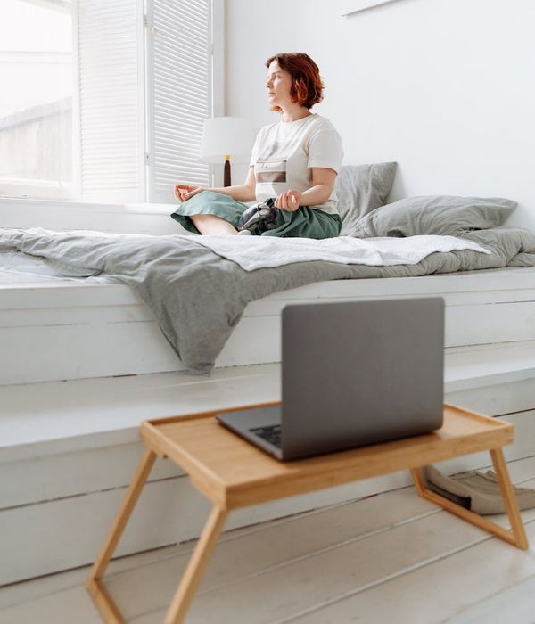 Woman in a calming yoga pose, bathed in soft morning light.